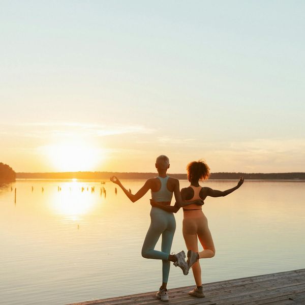 Person stretching peacefully outdoors during sunrise.